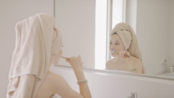 Tonårstjej borstar tänderna i badrummet på morgonen — Stockvideo