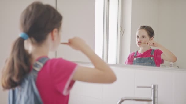Liten flicka borsta tänderna i badrummet på morgonen — Stockvideo