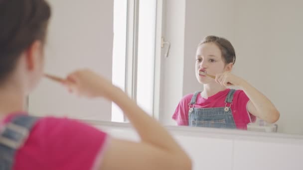 Liten flicka borsta tänderna i badrummet på morgonen — Stockvideo