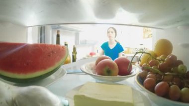 POV, buzdolabının içinden kapıyı açan ve yemeği dışarı çıkaran bir kızın fotoğrafını çekti.