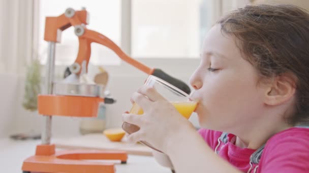 Young cute girl drinking a glass of freshly squeezed orange juice — Stock Video