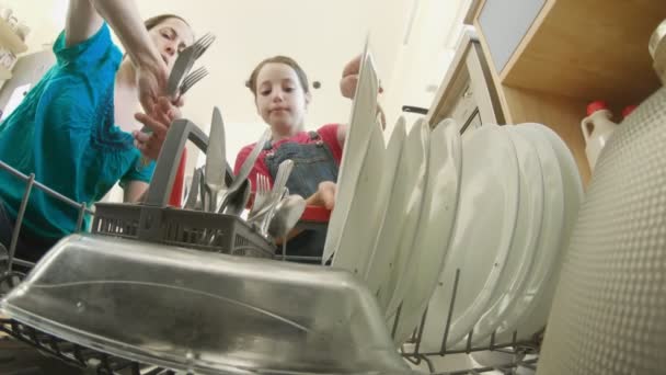 Niña ayudando a su madre a llenar el lavavajillas con platos sucios — Vídeos de Stock