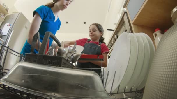 Két lány megtölti a mosogatógépet piszkos edényekkel. — Stock videók