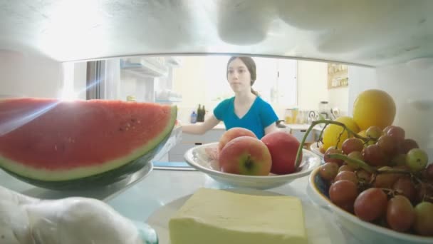 POV schot van binnenuit een koelkast van meisje openen van de deur en het nemen van voedsel — Stockvideo