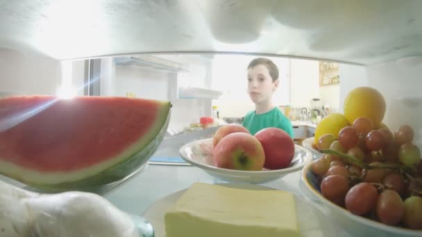 POV, buzdolabının içinden kapıyı açan ve yiyecekleri alan bir çocuğun fotoğrafını çekti. — Stok video