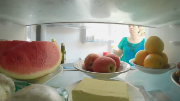 POV, bir buzdolabının içinde kapıyı açan ve yiyecekleri alan bir kadının fotoğrafını çekti. — Stok video