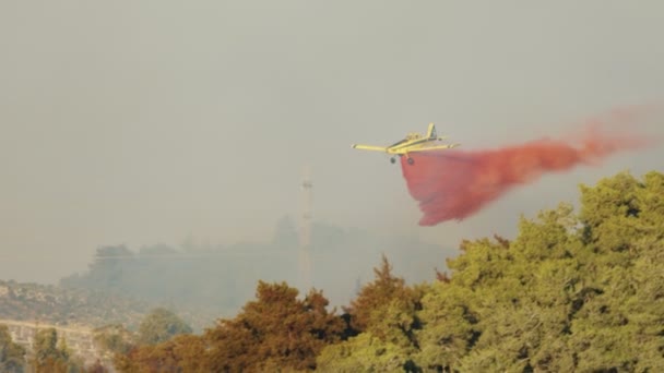 Fire fighter plane drops fire retardant on a forest fire in the hills — Stock Video