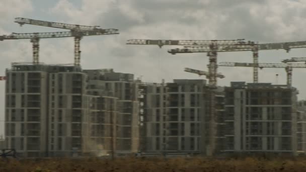 Большая строительная площадка с большим количеством кранов, работающих над зданиями — стоковое видео