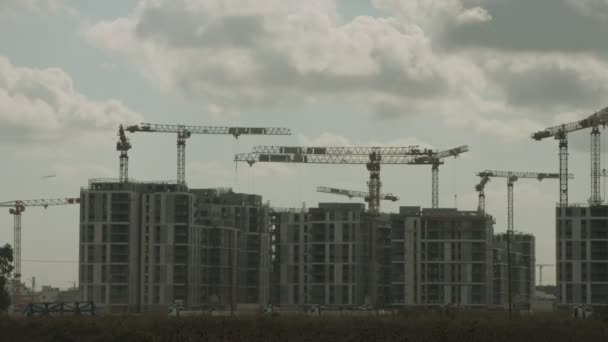 Egy nagy építési terület időrendje, ahol sok daru dolgozik épületek felett — Stock videók
