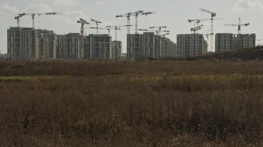 Binaların üzerinde çalışan vinçleri olan büyük bir inşaat alanı.