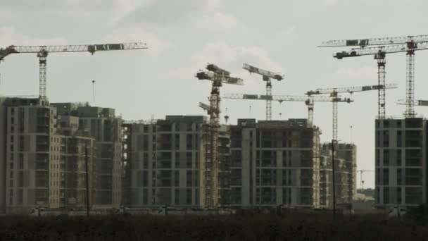 Большая строительная площадка с большим количеством кранов, работающих над зданиями — стоковое видео
