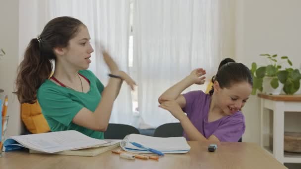 Две сестры дерутся и смеются во время подготовки домашней работы — стоковое видео