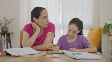 Anne, evde eğitim görürken küçük kızına ödevlerini hazırlamasında yardım ediyor.