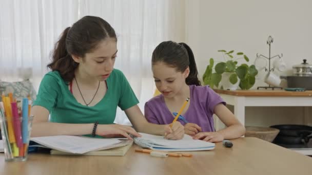 Tinédzser lány segít a fiatal húgának a házi feladatban a COVID-19 világjárvány alatt — Stock videók