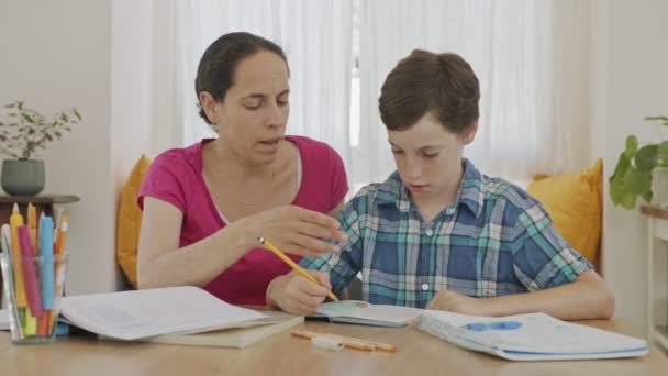 Matka pomaga młodemu synowi przygotować pracę domową podczas nauki w domu — Wideo stockowe