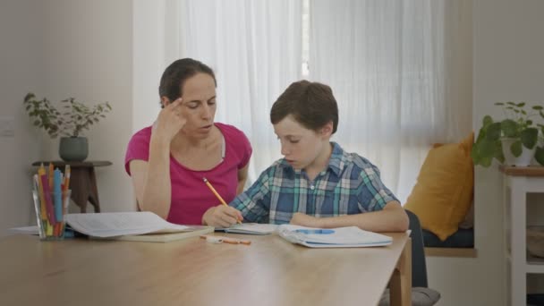 Moeder helpen haar jonge zoon voor te bereiden huiswerk tijdens thuisonderwijs — Stockvideo