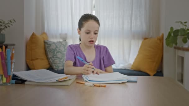 Genç kız evde oturuyor ve okul için ödev hazırlıyor. — Stok video