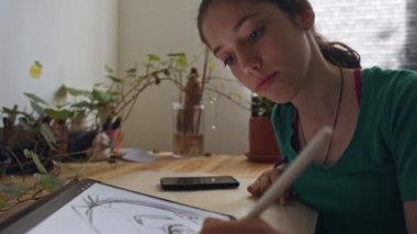 Tablet bilgisayar ve elektronik kalem kullanan genç bir kız çiziyor.
