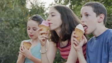 Çocuklar birlikte dondurma yiyor, eğleniyor ve gülüyorlar.