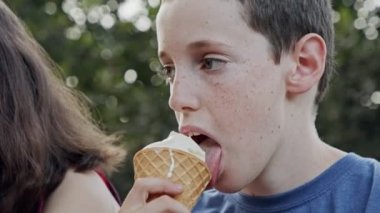 Dondurma yiyen genç bir çocuk, eğleniyor ve gülüyor.