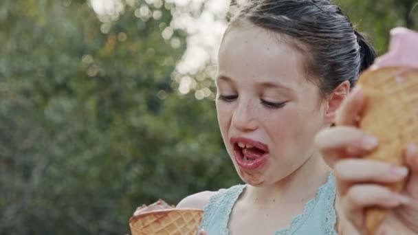 若い女の子はコーンからアイスクリームを食べます,楽しんで笑って — ストック動画