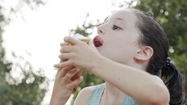 Bir külahtan dondurma yiyen genç kız, eğleniyor ve gülüyor.