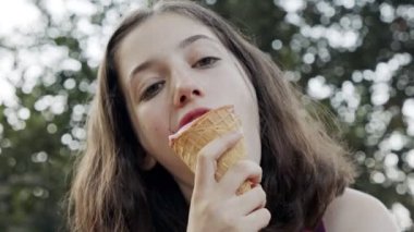 Bir külahtan dondurma yiyen genç kız, eğleniyor ve gülüyor.