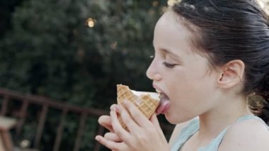 Bir külahtan dondurma yiyen genç kız, eğleniyor ve gülüyor.