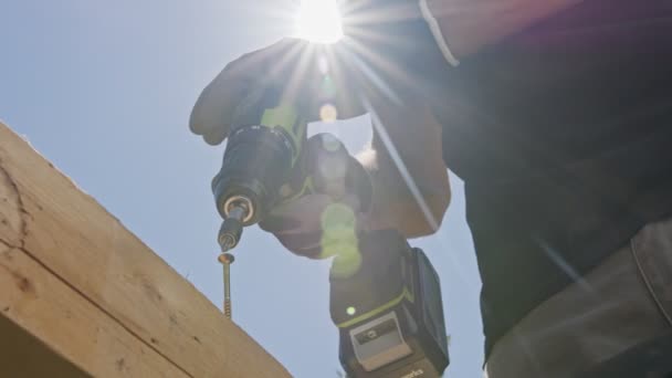 Movimiento lento de un hombre que usa un destornillador eléctrico para introducir un tornillo en la madera — Vídeos de Stock