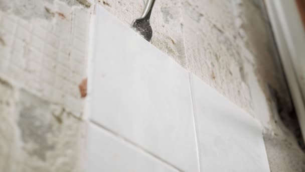 Slow motion of a rotary hammer breaking ceramic tiles off a wall — Stock Video