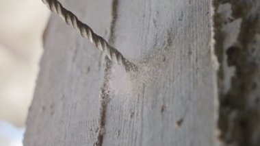 Beton duvarda delik açan bir adam. Kapalı alanda ağır çekimde çalışır.