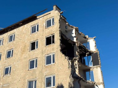 Açık mavi gökyüzünün altında iç kısımları açık olan kısmen yıkılmış bir bina..