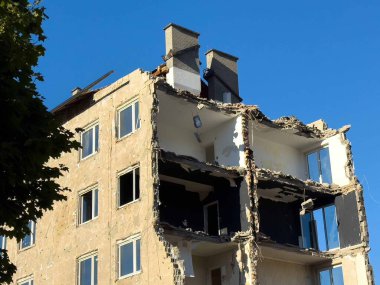 Açık mavi gökyüzüne karşı kısmen yıkılmış apartman.