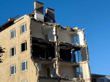 Açık mavi gökyüzüne karşı iç kısımları olan çok katlı binanın kısmen yıkılması.