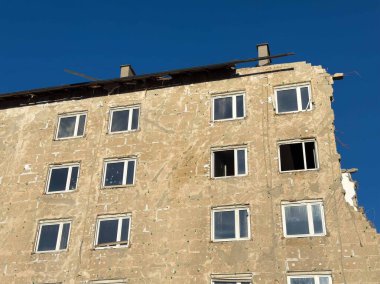 Harap olmuş apartmanın dış tarafı açık mavi gökyüzüne karşı..