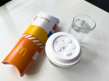 Mcwrap, kahve fincanı ve masanda su bardağı olan fast food yemeği..