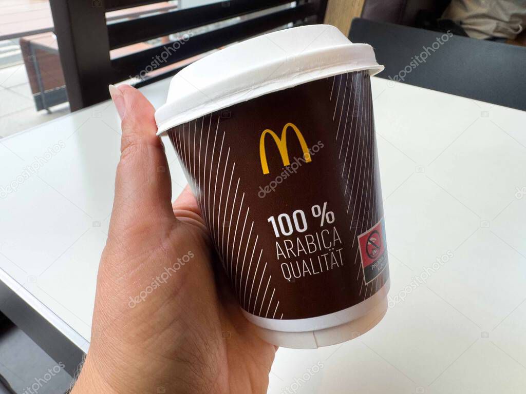 Hand holding mcdonald's coffee cup with 100% arabica print.