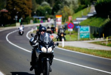 Faaker See, Avusturya - 01 Eylül 2025: Avrupa Bisiklet Haftası boyunca kask takan erkek motosikletli parlak siyah motosiklet, Harley-Treffen 'in özünü yakalıyor