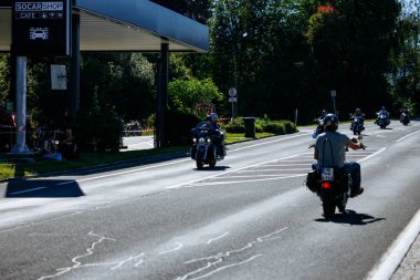 Faaker See, Avusturya - 01 Eylül 2025: Motosikletçiler, Harley-Davidson bisikletleri ve yemyeşil otlakların yer aldığı güneşli bir günde Avrupa Bisiklet Haftası 'nın tadını çıkarıyorlar