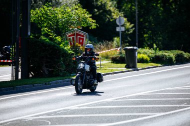 Faaker See, Avusturya - 01 Eylül 2025: Harley-Davidson sürücüsü, yemyeşil ve canlı ambiyansla çevrili Avrupa Bisiklet Haftası boyunca manzaralı yolda yol alıyor