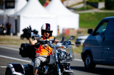 Faaker See, Avusturya - 01 Eylül 2025: Turuncu yelekli erkek motorcu Harley-Davidson motosikleti Avrupa Bisiklet Haftası 'nda, Harley-Treffen' in canlı ruhunu yakalıyor