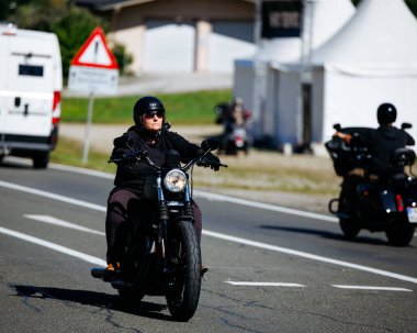 Faaker See, Avusturya - 01 Eylül 2025: Avrupa Bisiklet Haftası sırasında siyah Harley motosikletine binen kadın, macera ruhunu yakalıyor
