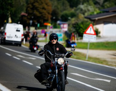 Faaker See, Avusturya - 01 Eylül 2025: Siyah deri ceketli erkek motorcu Avrupa Bisiklet Haftası sırasında Harley-Davidson motosikleti sürüyor