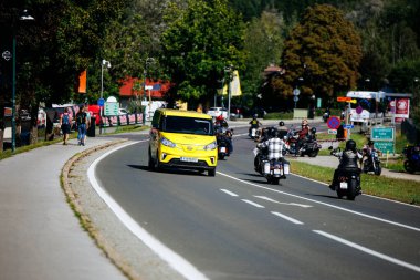 Faaker See, Avusturya - 01 Eylül 2025: Avrupa Bisiklet Haftası sırasında, yemyeşil ağaçlar ve canlı festival atmosferiyle çevrili motosikletler