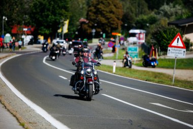 Faaker See, Avusturya - 01 Eylül 2025: Harley-Davidson motosikletçisi Avrupa Bisiklet Haftası sırasında pitoresk yolda motosiklet sürerek motosiklet kültürünün özünü yakalıyor
