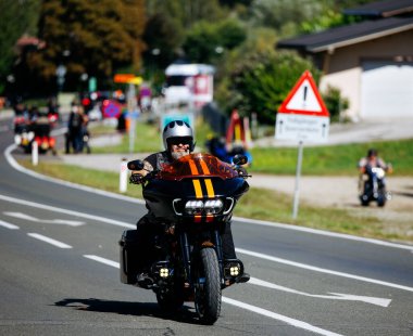 Faaker See, Avusturya - 01 Eylül 2025: Harley-Davidson sürücüsü Avrupa Bisiklet Haftası 'nda motosikletçiler ve güzel manzaralarla çevrili manzaralı yolun tadını çıkarıyor