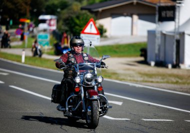 Faaker See, Avusturya - 01 Eylül 2025: Avrupa Bisiklet Haftası 'nda Harley-Davidson motosikletli erkek motosikletçi, Harley-Treffen buluşmasının coşkulu ruhunu yakalıyor