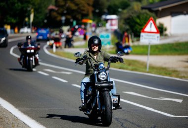 Faaker See, Avusturya - 01 Eylül 2025: Avrupa Bisiklet Haftası boyunca Harley-Davidson motosikletine binen kadın motosikletçi macera ruhunu yakaladı