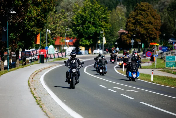 Faaker See, Avusturya - 01 Eylül 2025: Motosikletçiler Avrupa Bisiklet Haftası sırasında Harley-Davidson motosikletleri ve yemyeşil otlakların yer aldığı pitoresk bir yolda ilerliyorlar