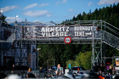 Faaker See, Avusturya - 01 Eylül 2025: Avrupa Bisiklet Haftası: Arneitz Köyü tabelasında Burnout Çadırı, hevesli motosiklet sürücüleri ve manzaralı arka plan